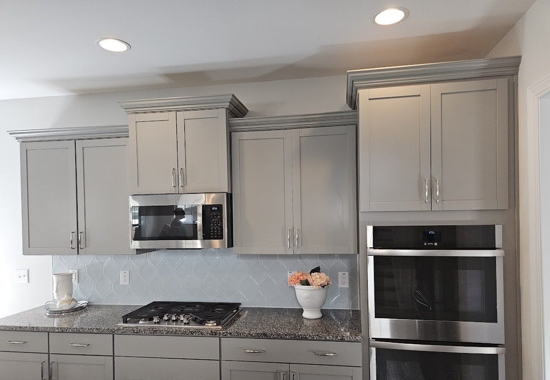 A kitchen with gray cabinets and stainless steel appliances