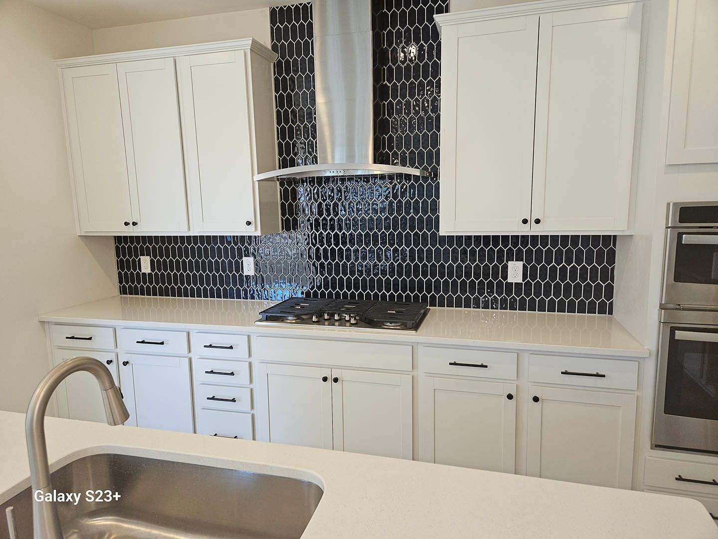 A kitchen with white cabinets , stainless steel appliances , and a sink.