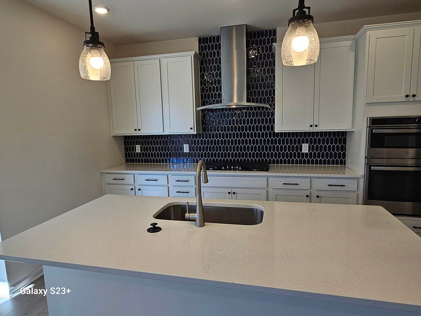 A kitchen with white cabinets , a sink , and a stove.