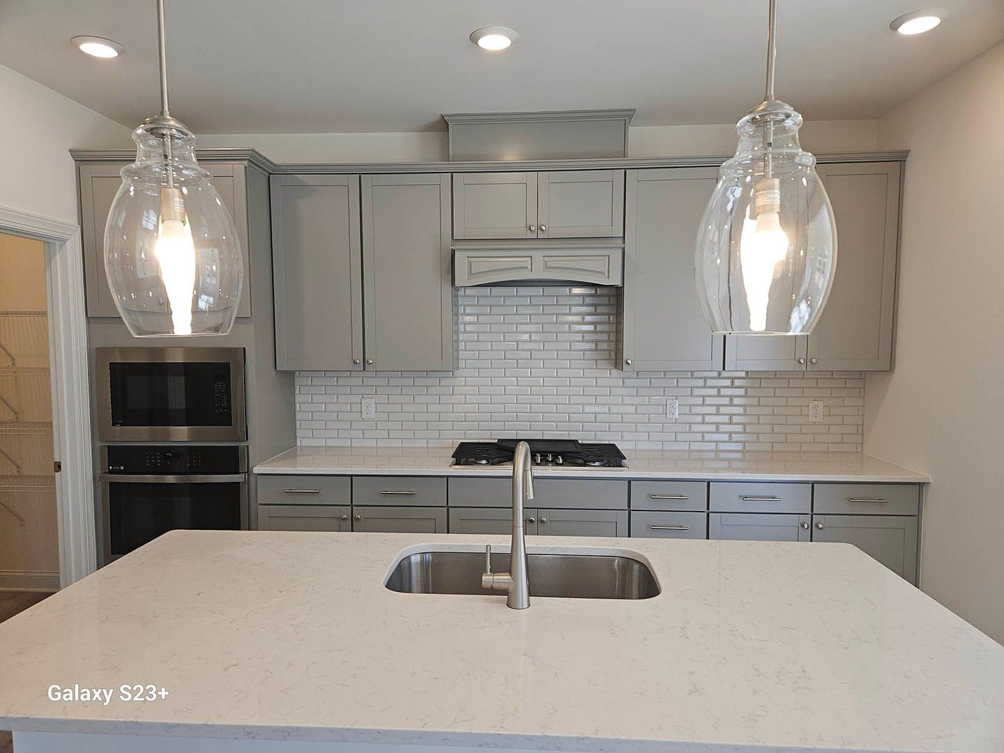 A kitchen with gray cabinets and a stainless steel sink