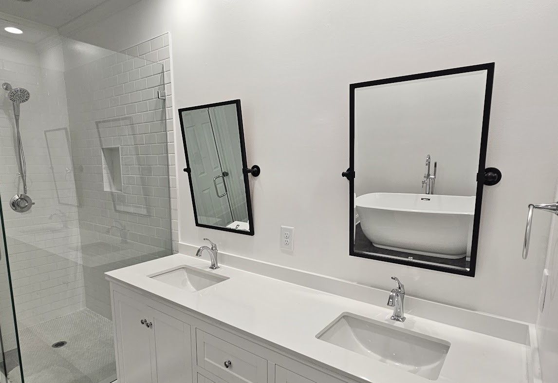 A bathroom with two sinks , two mirrors and a tub.