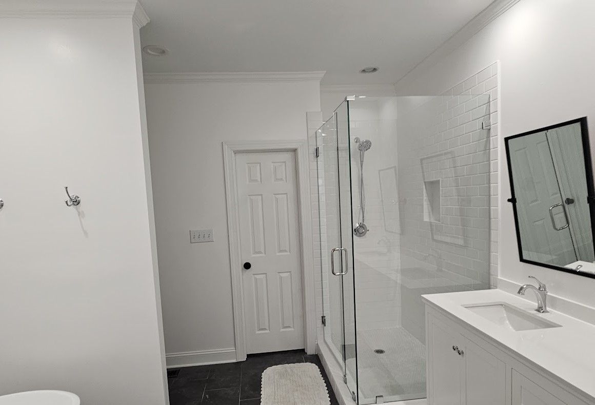 A bathroom with a walk in shower , sink , toilet and mirror.