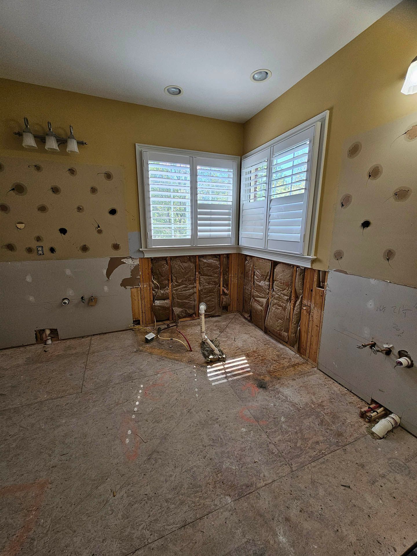 A bathroom with a lot of holes in the walls and a window.