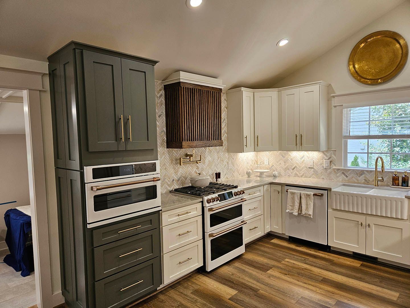 A kitchen with white cabinets , a stove , a sink , and a window.