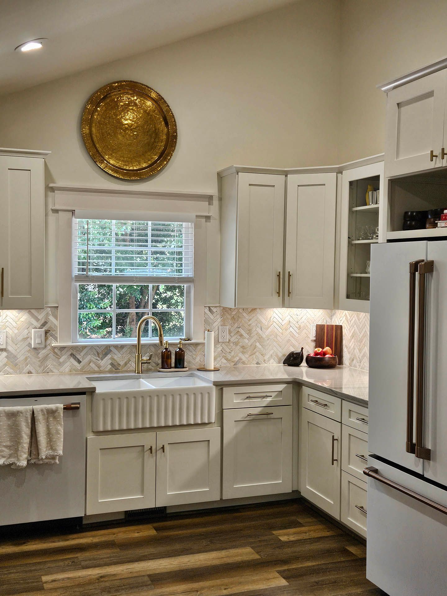 A kitchen with white cabinets , a sink , a refrigerator and a window.