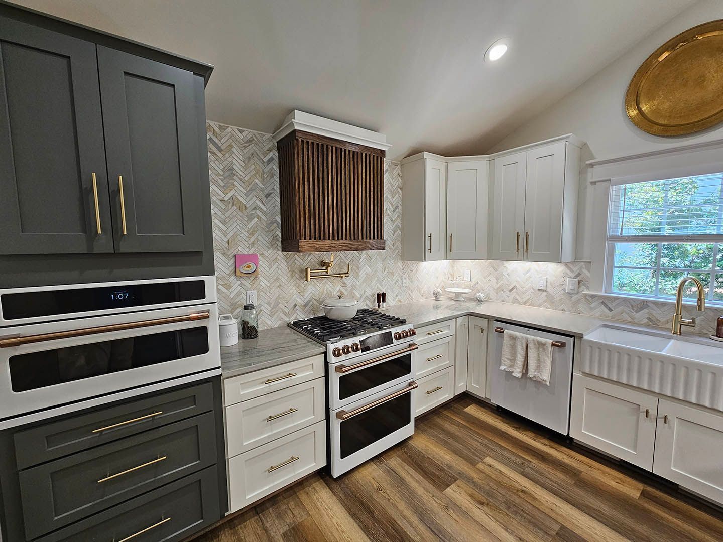 A kitchen with gray cabinets , white cabinets , a stove and a sink.