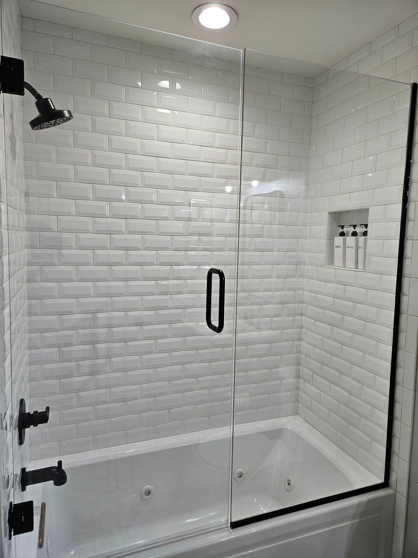 There is a bathtub in the shower with a glass door.