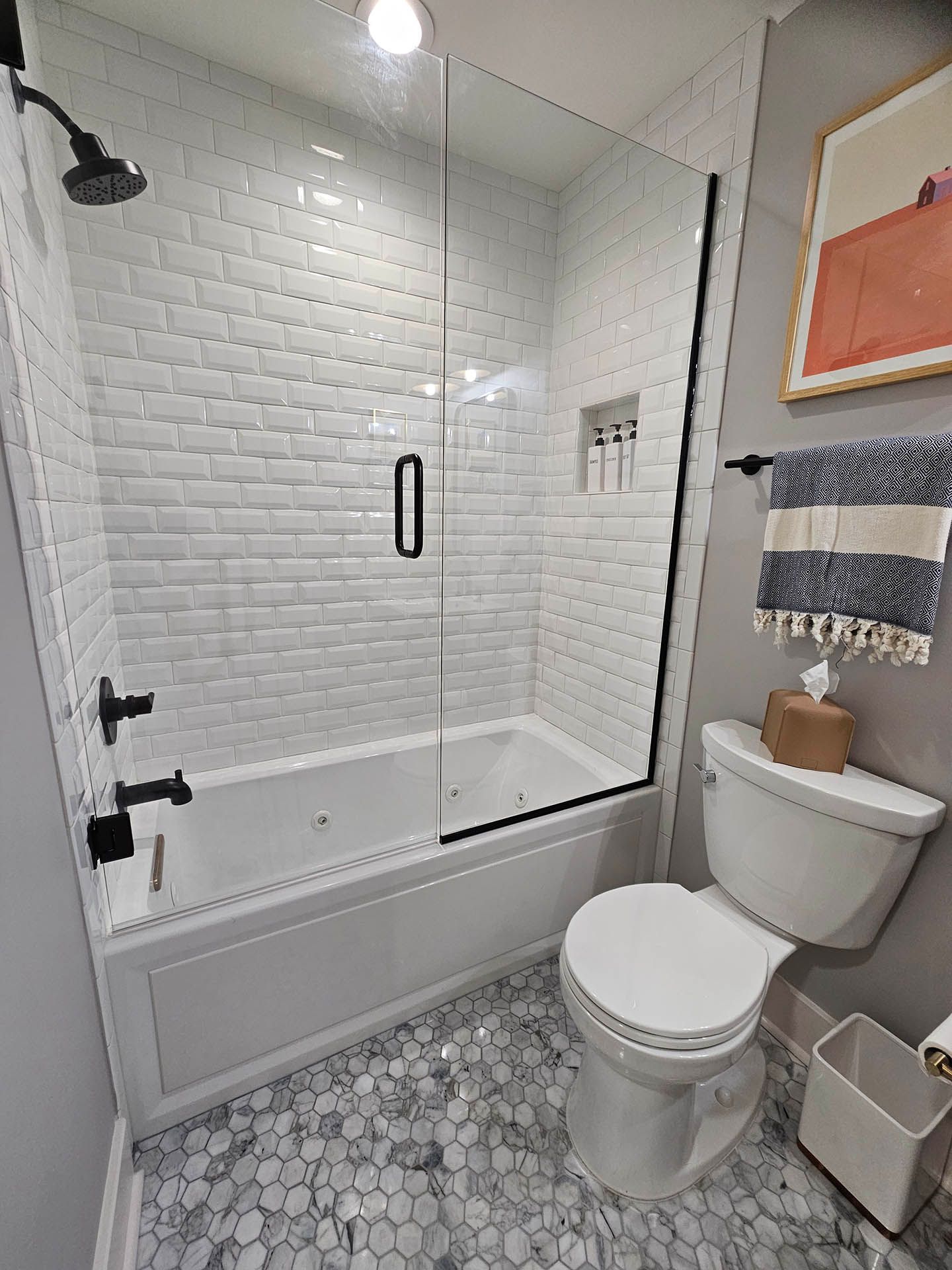 A bathroom with a tub , toilet , shower and glass door.