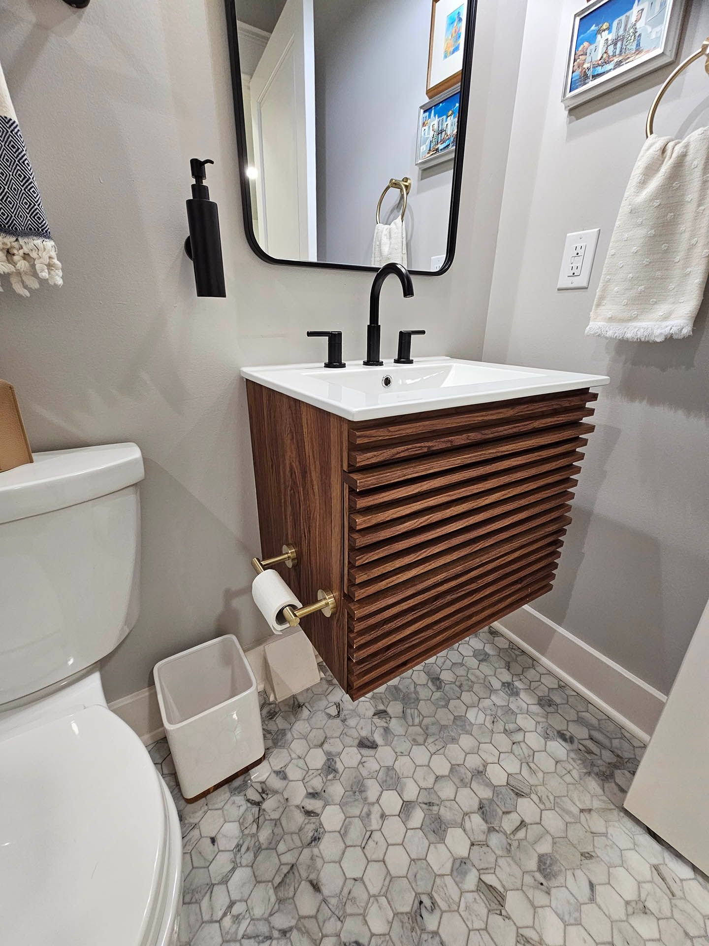 A bathroom with a sink , toilet , mirror and trash can.