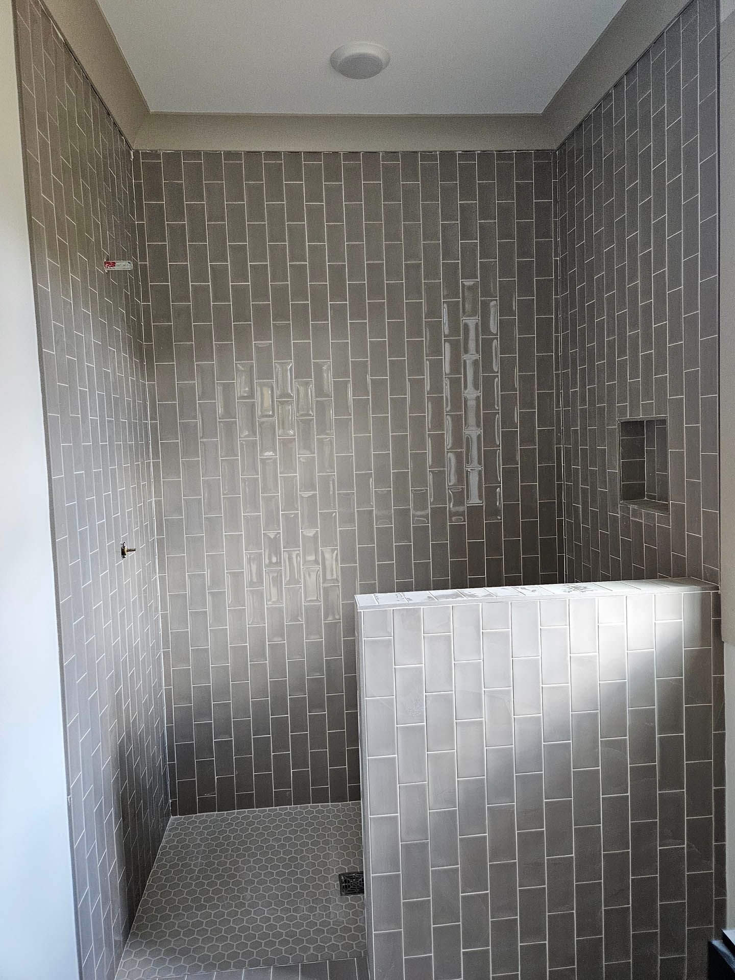 A bathroom with a walk in shower and a tiled wall.