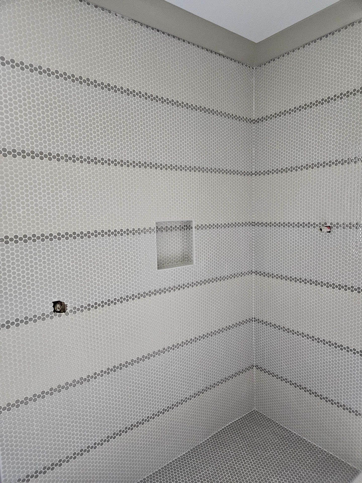 A shower stall with a tiled wall and a shower head.