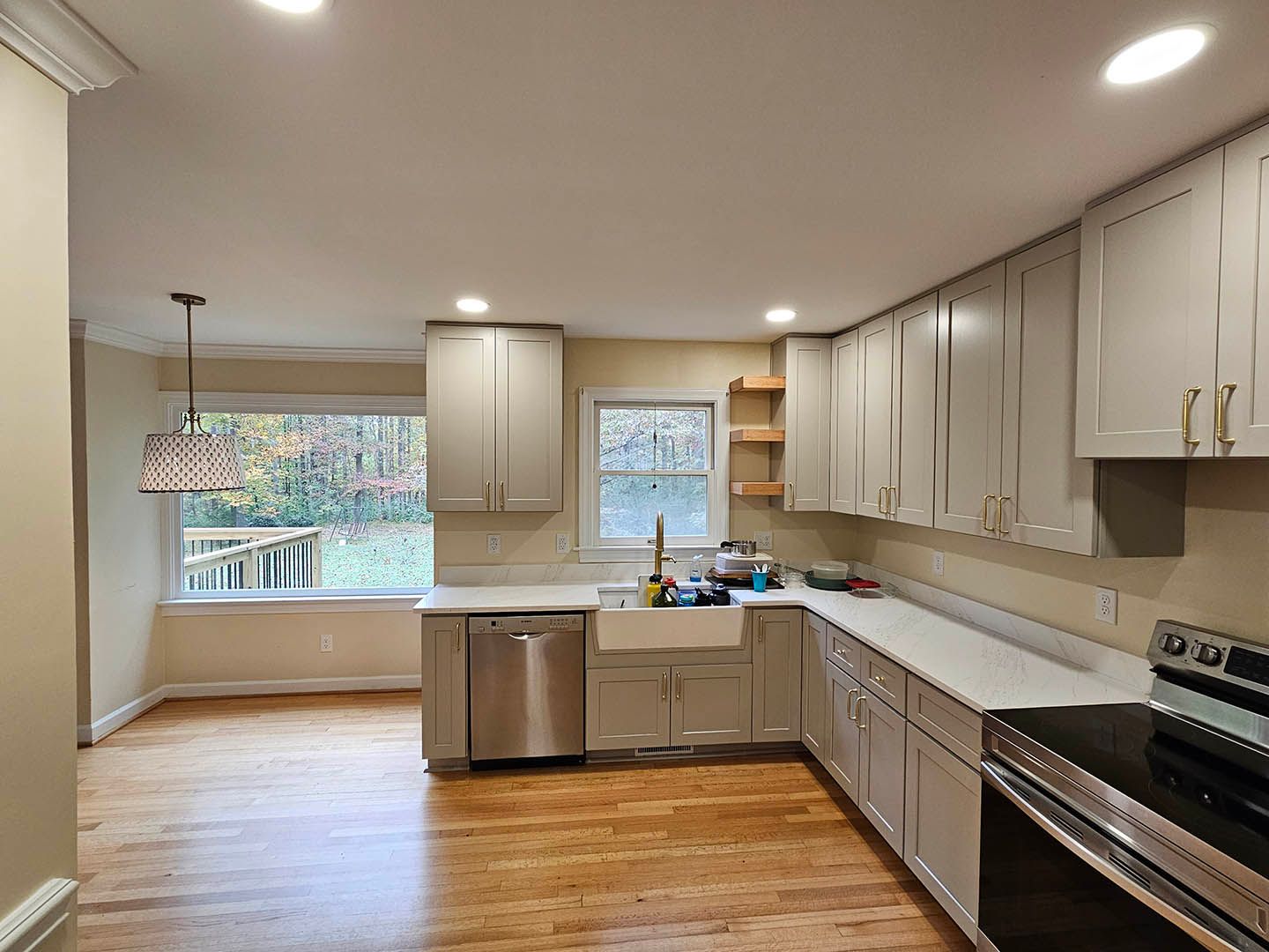 A kitchen with white cabinets , stainless steel appliances , a sink and a window.