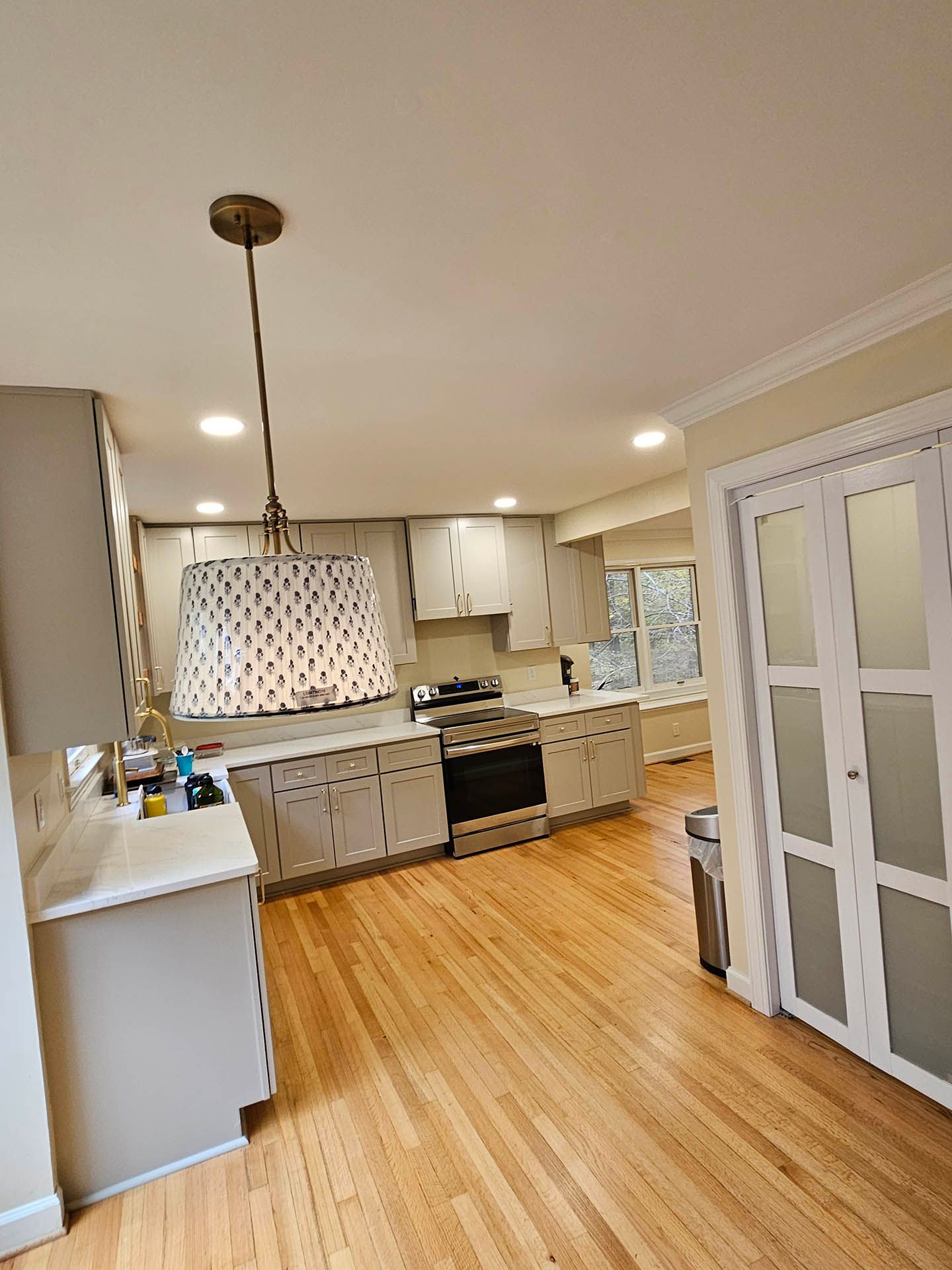 A kitchen with hardwood floors and white cabinets and a stove.