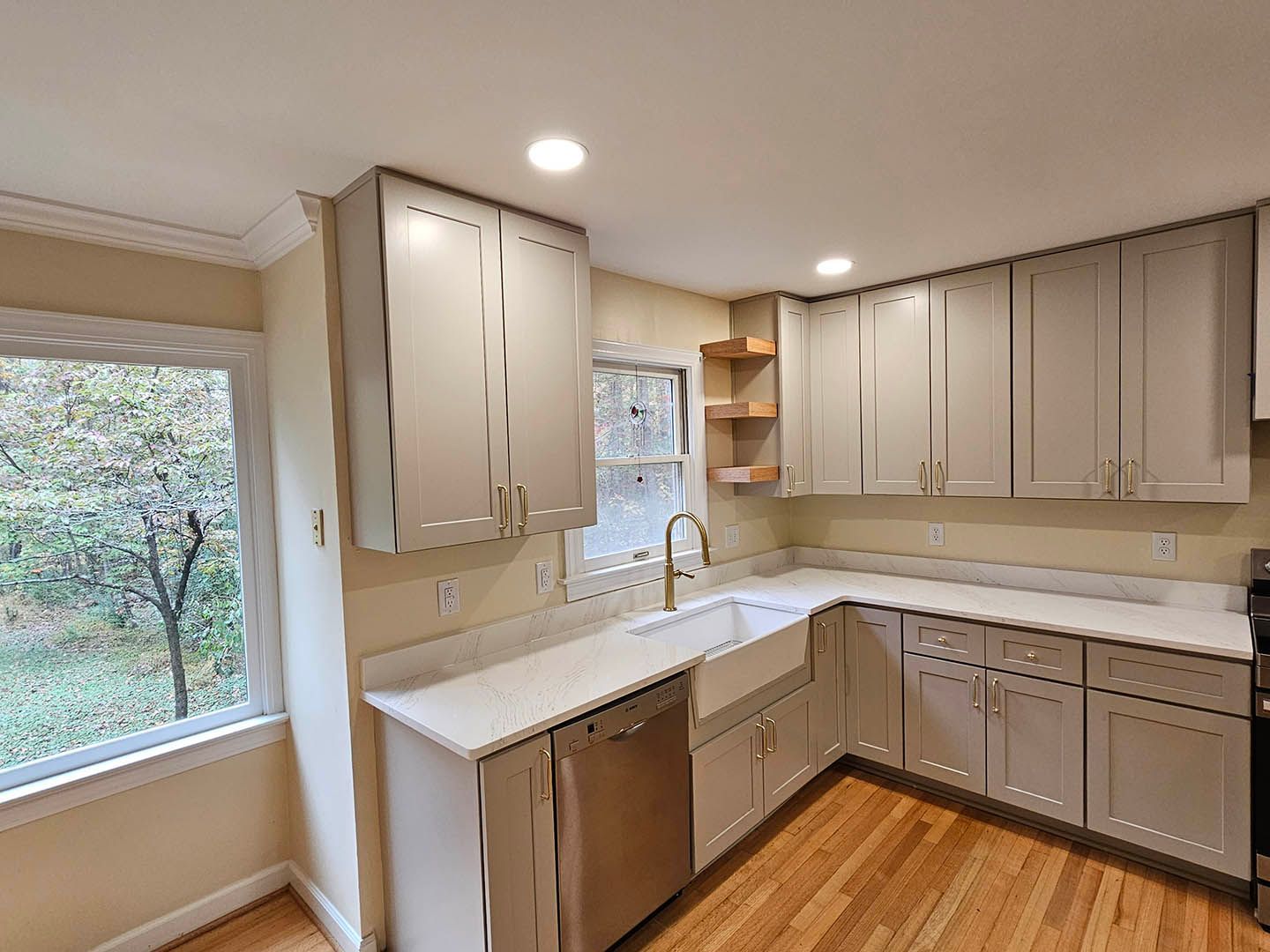 A kitchen with white cabinets , stainless steel appliances , a sink and a window.