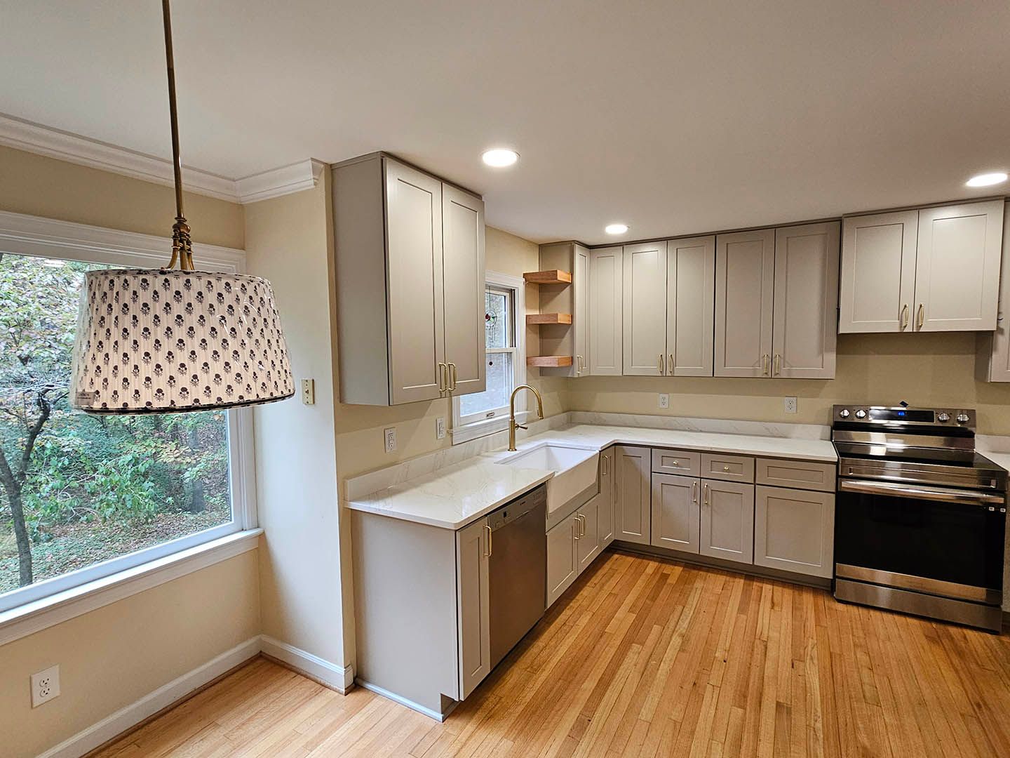 A kitchen with white cabinets , stainless steel appliances , a sink and a window.