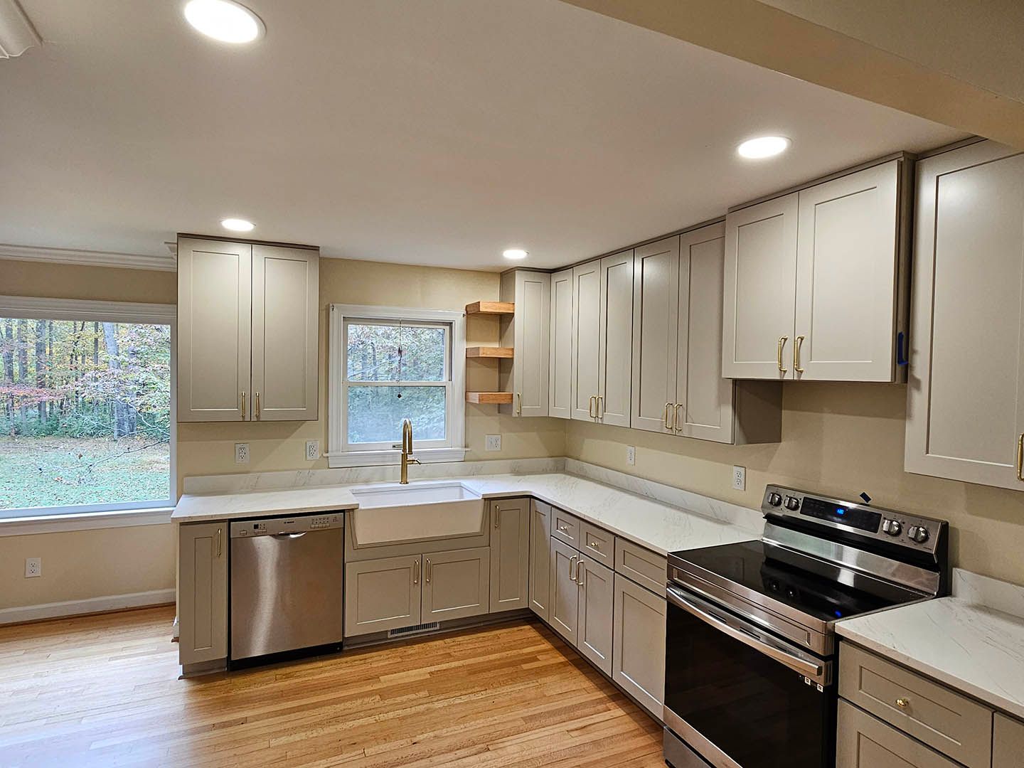 A kitchen with white cabinets , stainless steel appliances , a sink and a window.
