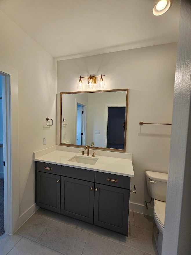 A bathroom with a sink , toilet and mirror.