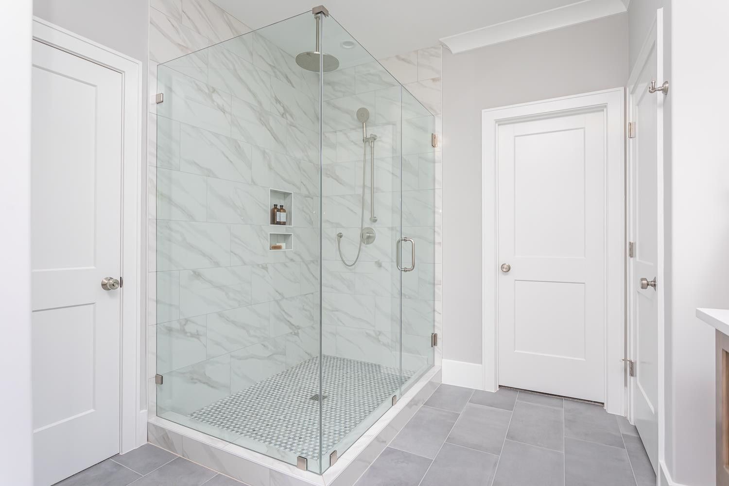 A bathroom with a walk in shower with a glass door.