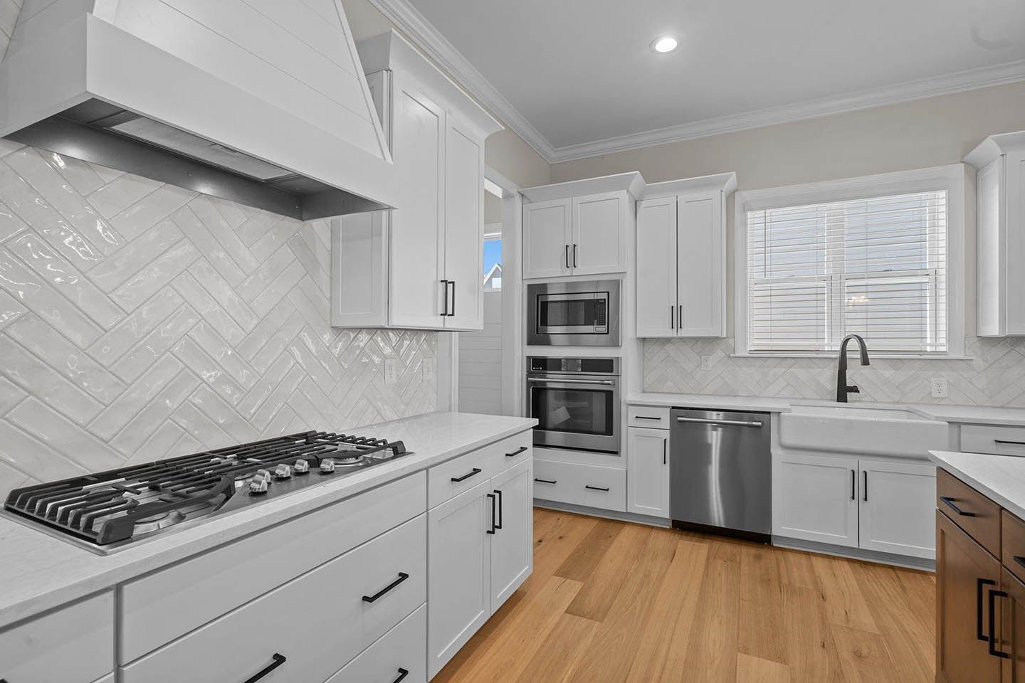 A kitchen with white cabinets , stainless steel appliances and hardwood floors.