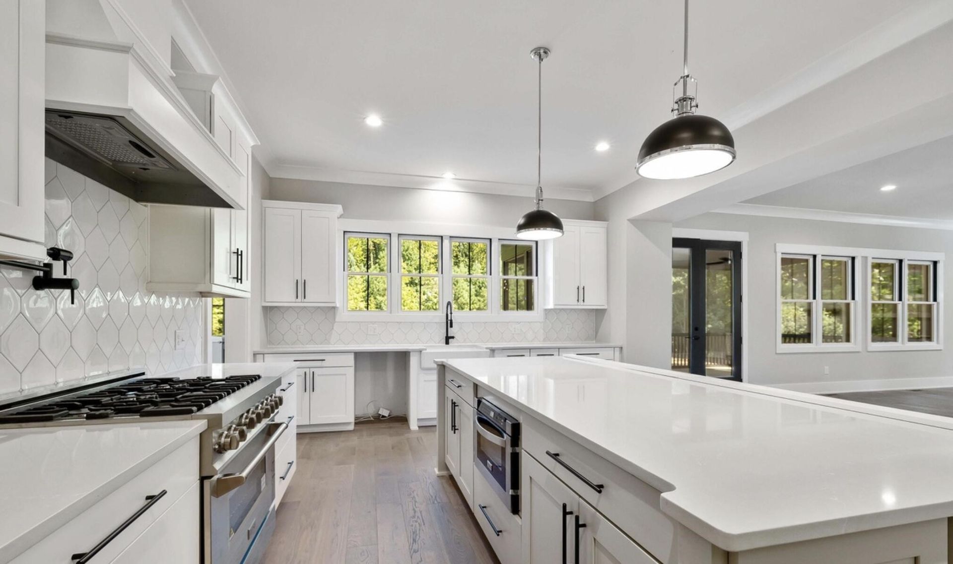 A kitchen with white cabinets , stainless steel appliances , and a large island.