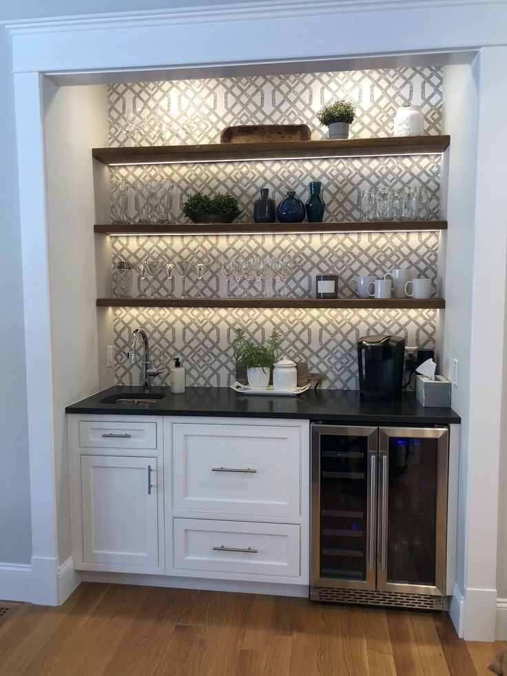 A kitchen with a wine cooler , sink , and shelves.