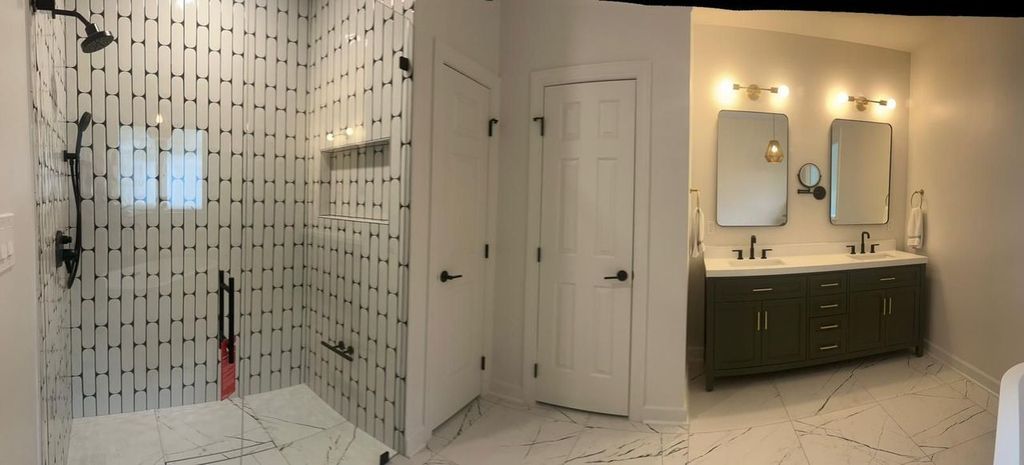 A bathroom with a walk in shower and two sinks.