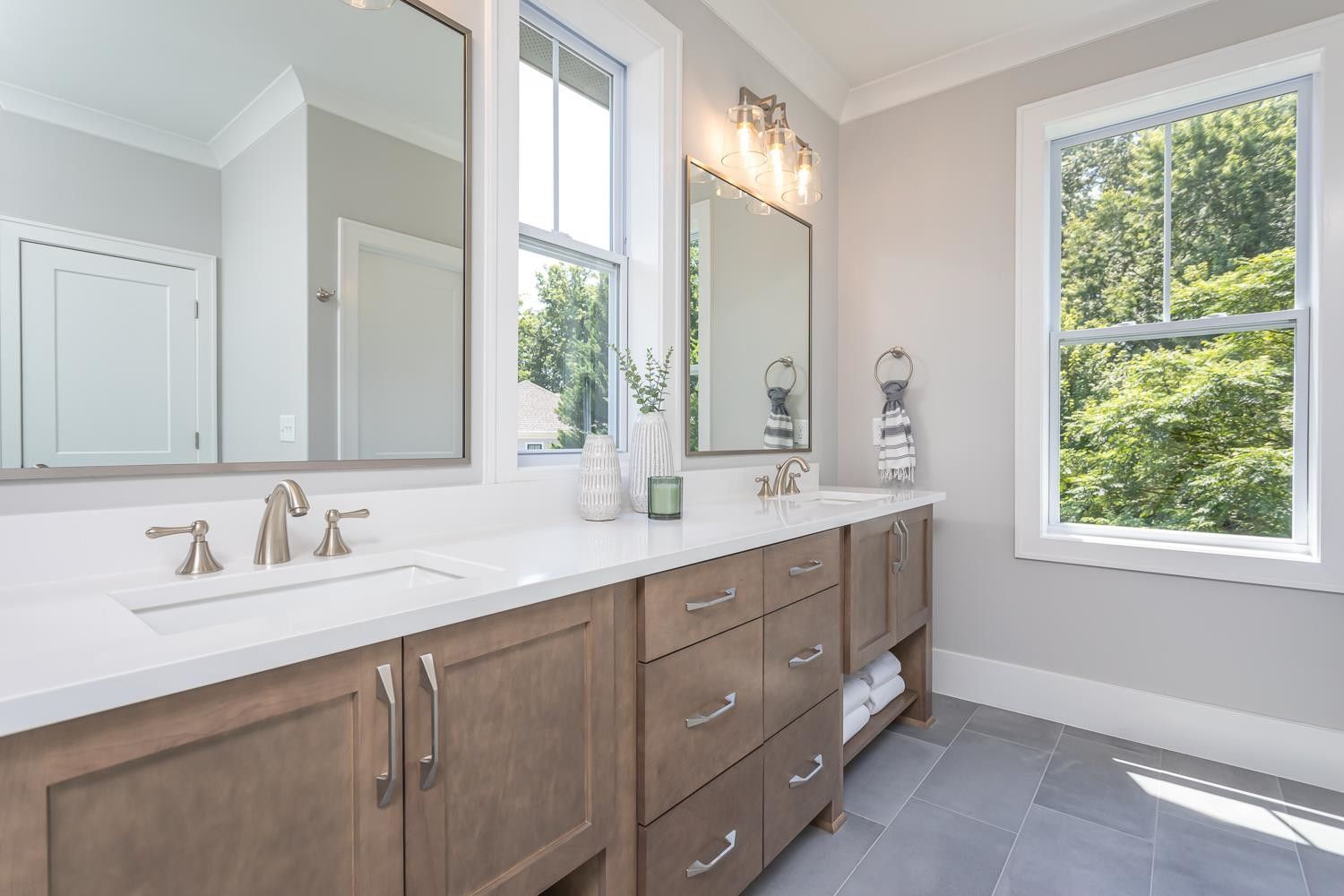 A bathroom with two sinks , two mirrors and two windows.