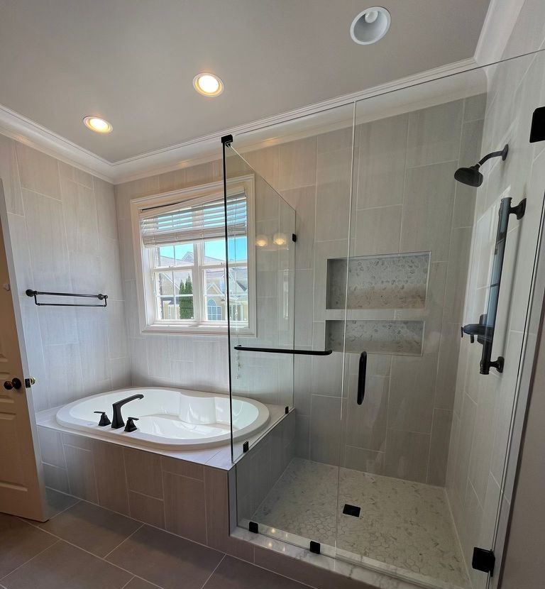 A bathroom with a tub and a shower with a glass door.