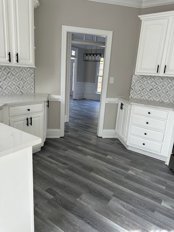 A kitchen with white cabinets and a wooden floor.