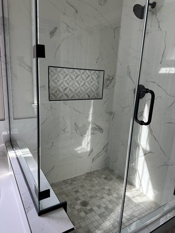 A bathroom with a walk in shower with a glass door.