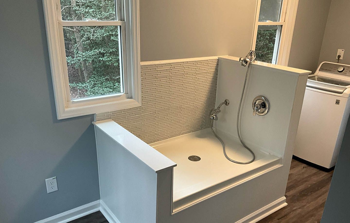 A dog washing station in a laundry room next to a window.