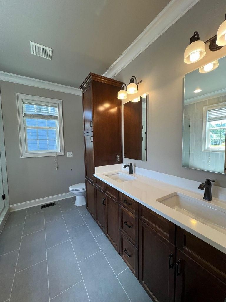 A bathroom with two sinks , a toilet , and a mirror.