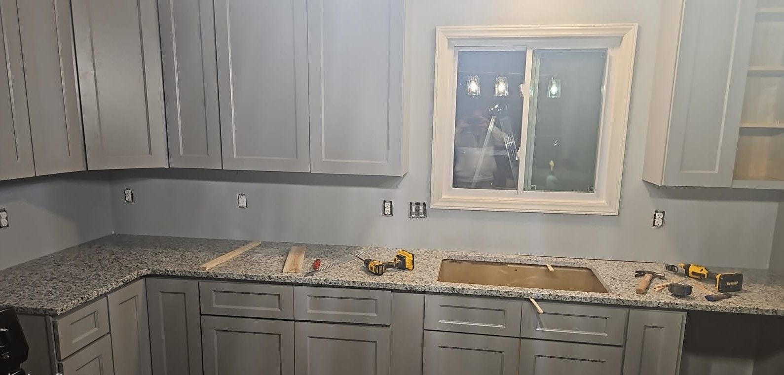 A kitchen with gray cabinets and granite counter tops is being remodeled.