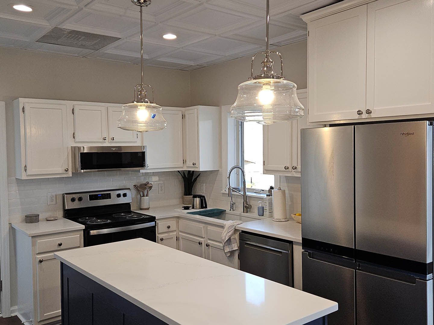 A kitchen with white cabinets , stainless steel appliances and a large island.