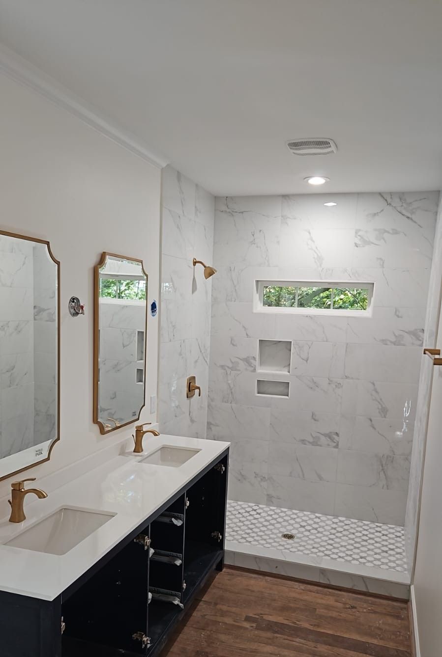 A bathroom with two sinks and a walk in shower.