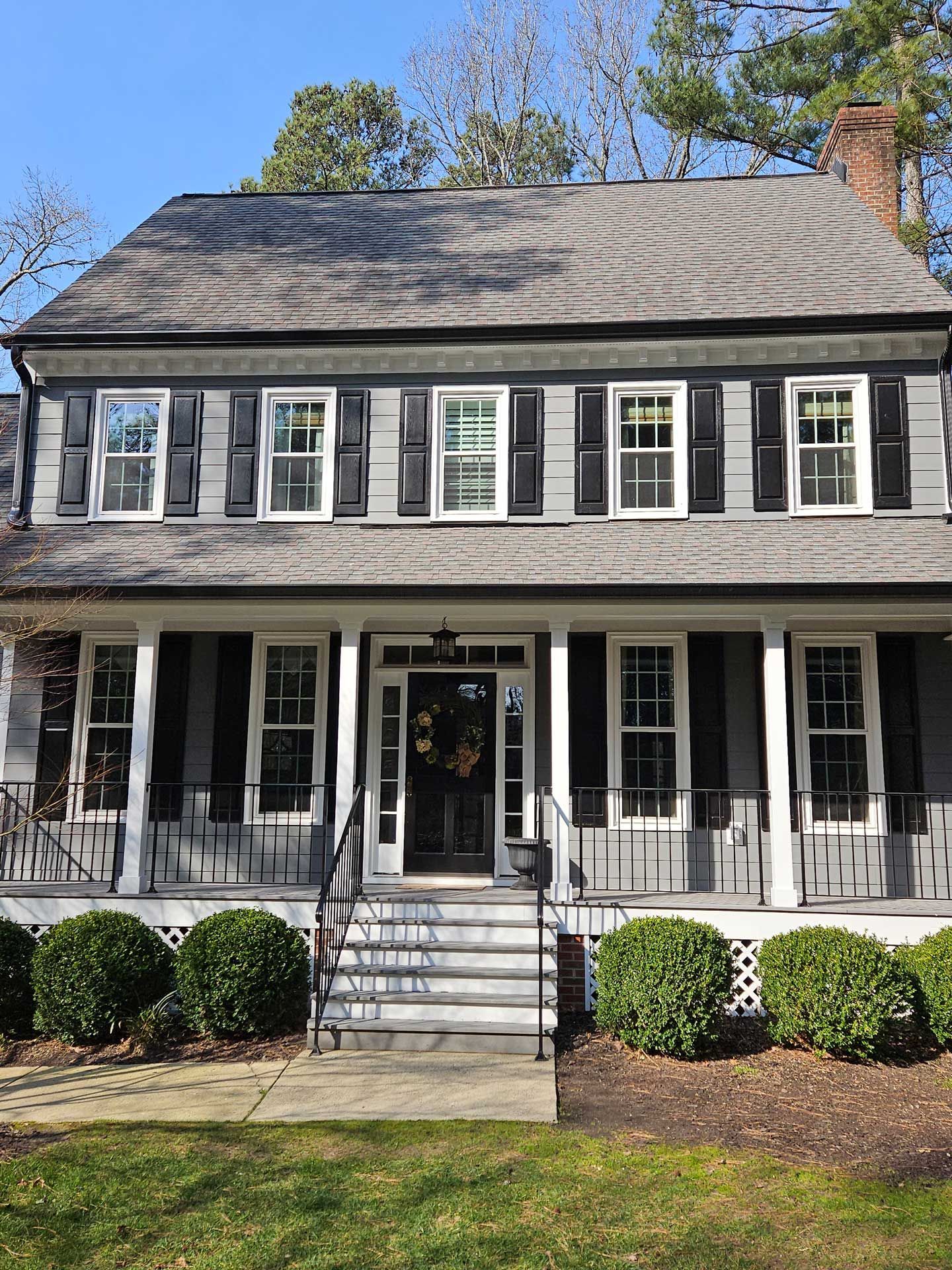 A large house with black shutters and a large porch