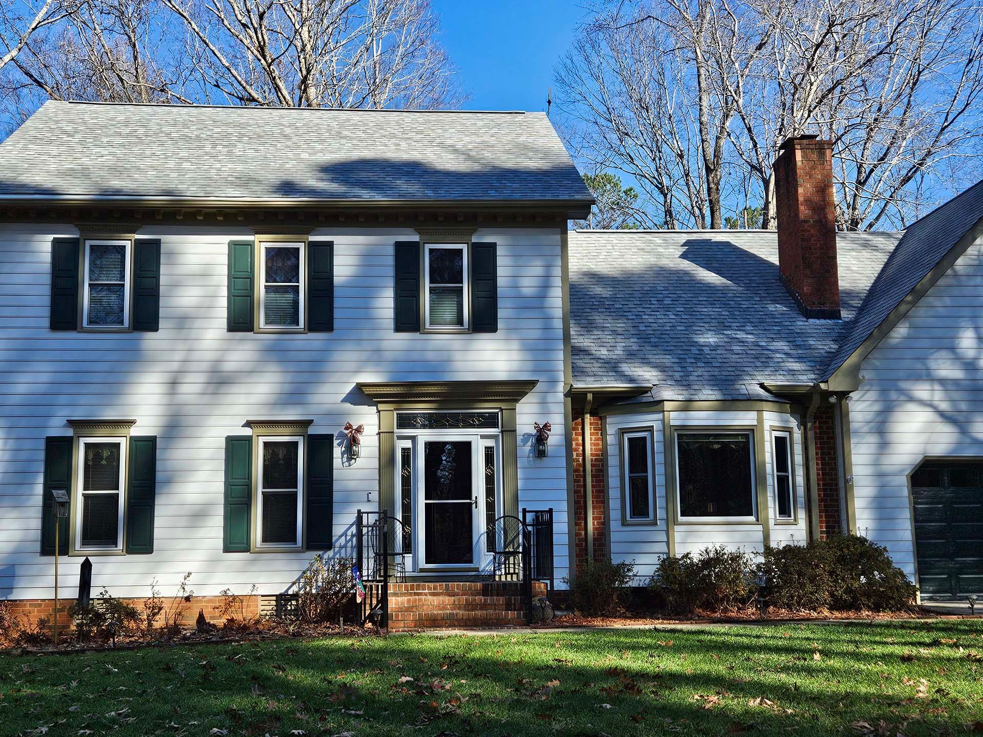 A white house with black shutters and a chimney