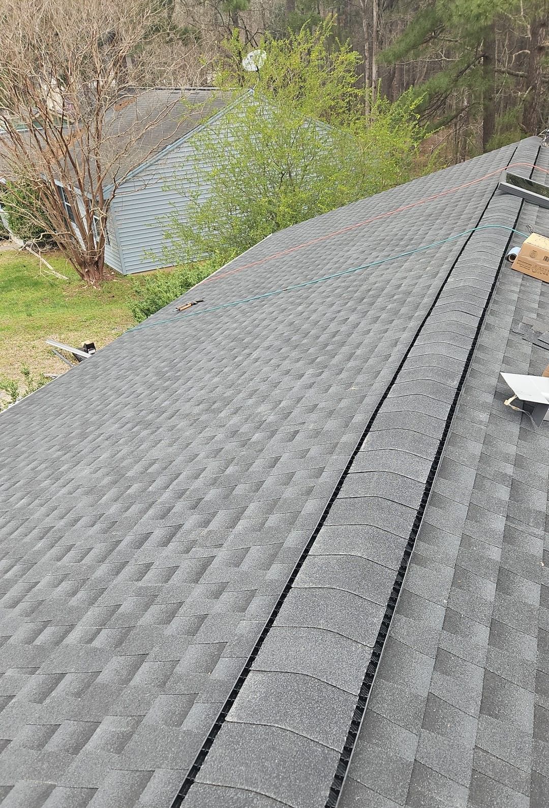 A roof with a lot of shingles on it and trees in the background.