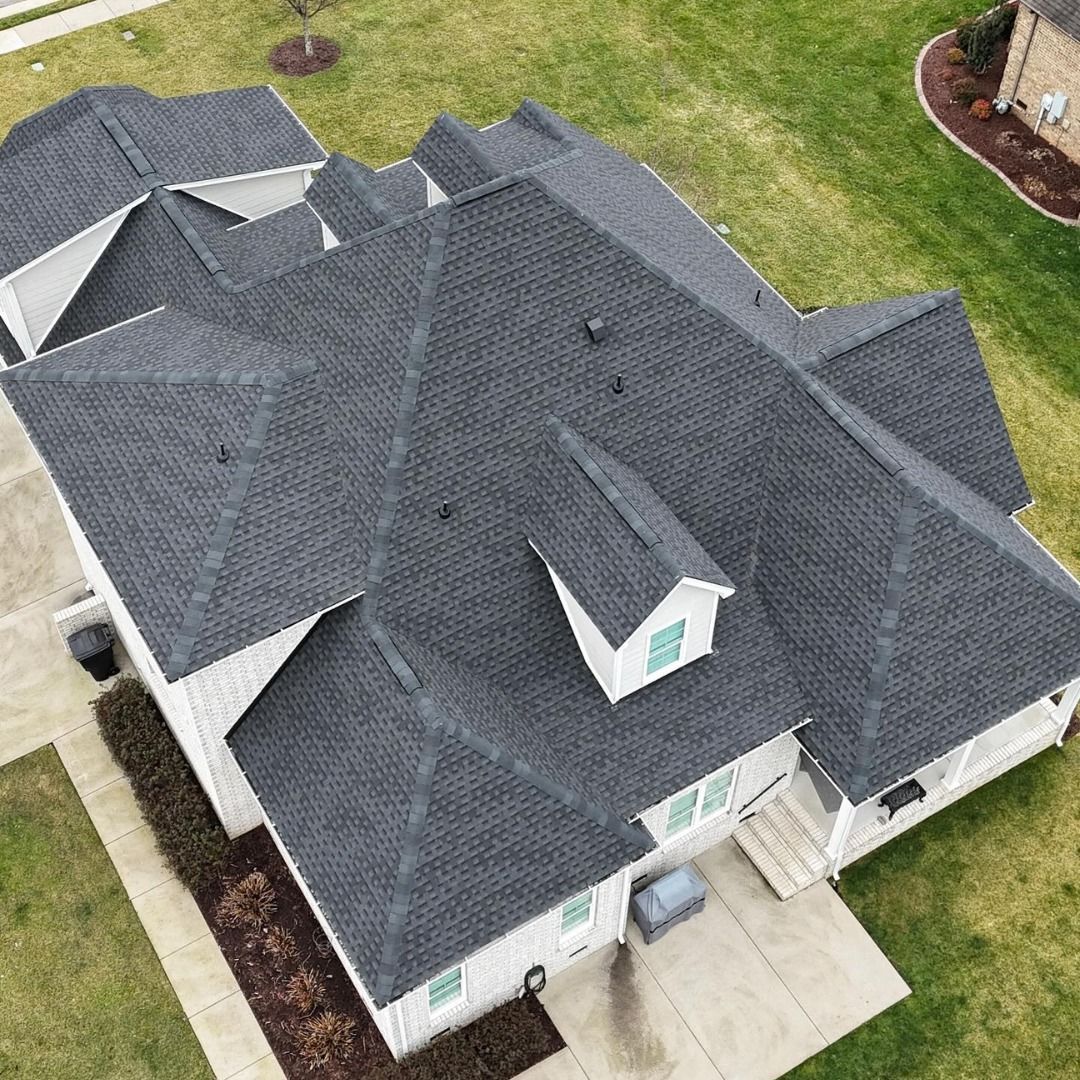 An aerial view of a large white house with a black roof.