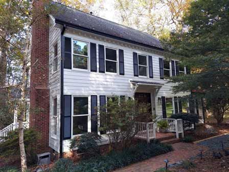 A large white house with black shutters and a brick chimney.
