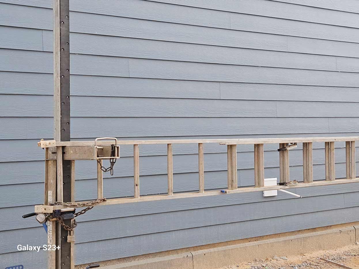 A ladder is attached to a pole in front of a building.