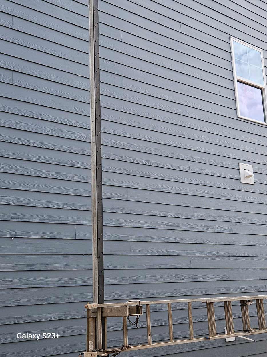 A ladder is leaning against the side of a house next to a window.