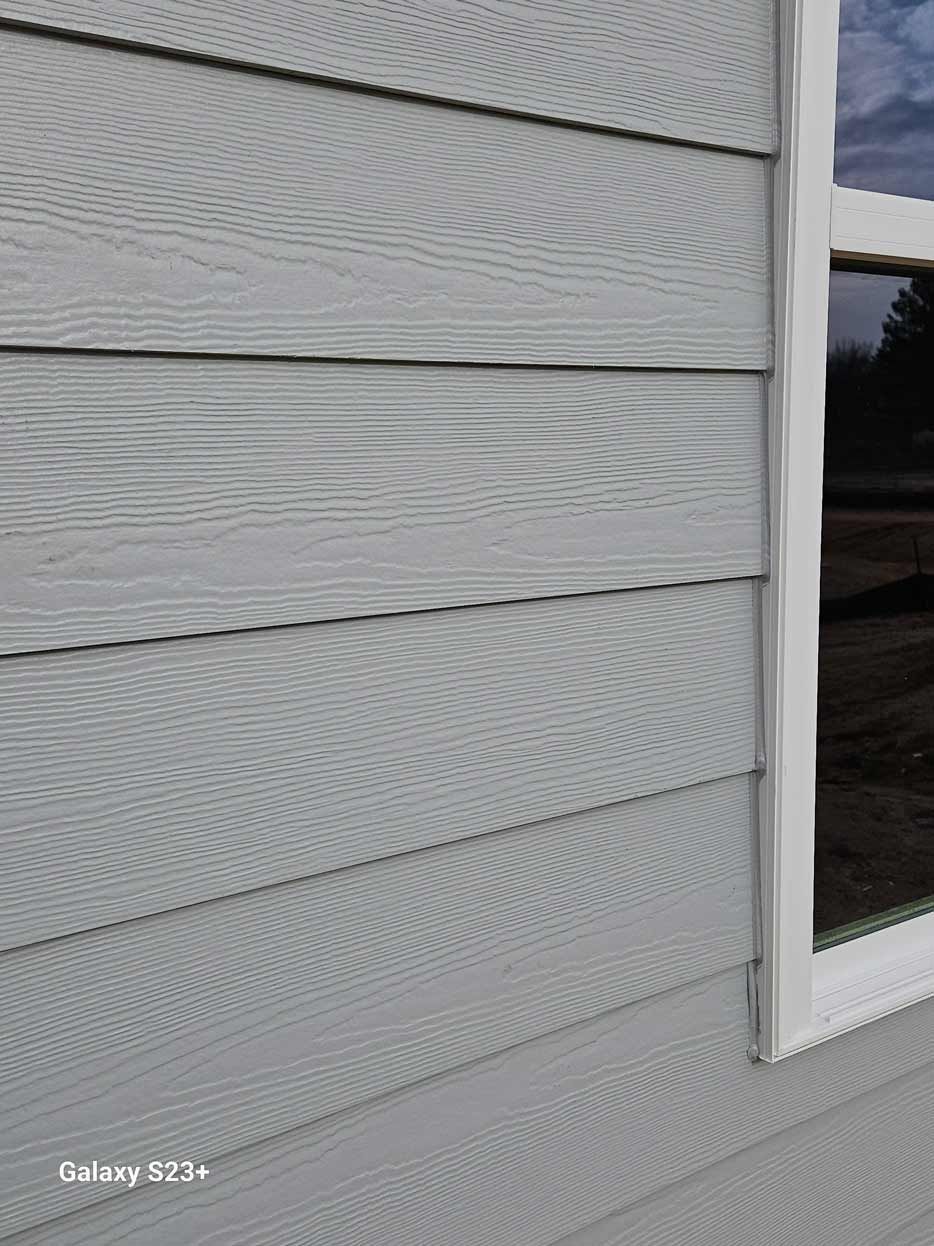 A close up of a white siding on a house with a window.