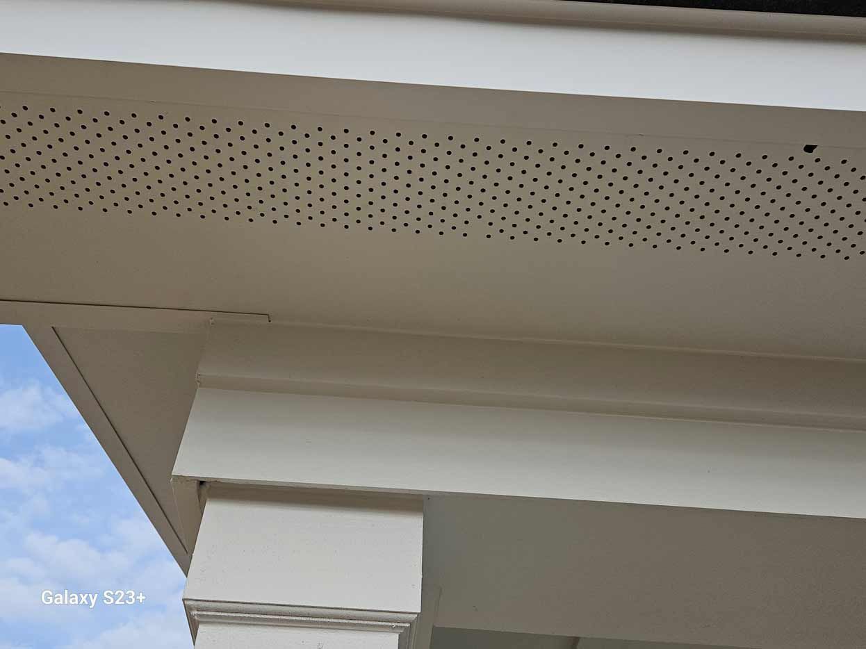 A close up of the ceiling of a house with a blue sky in the background.