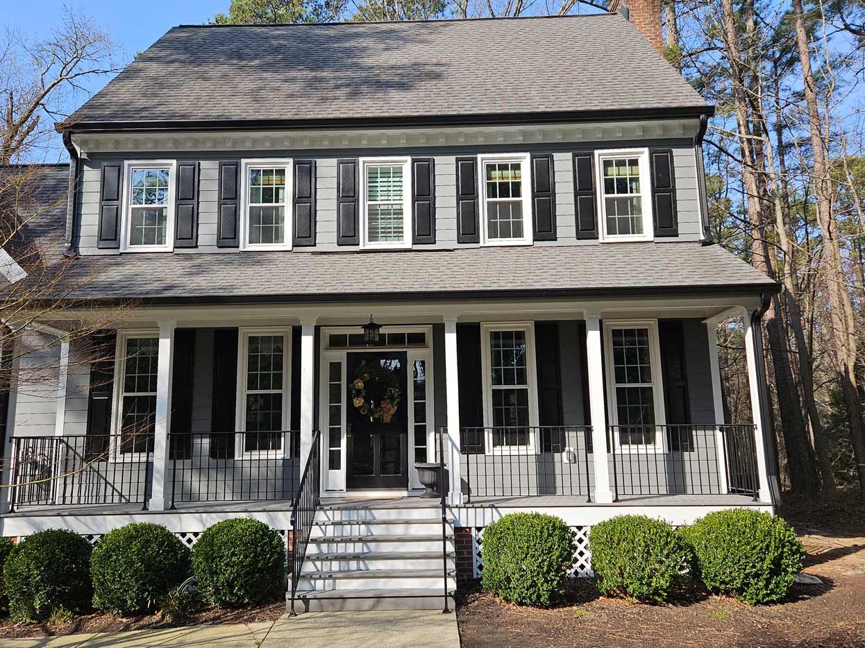 A large white house with black shutters and a large porch.