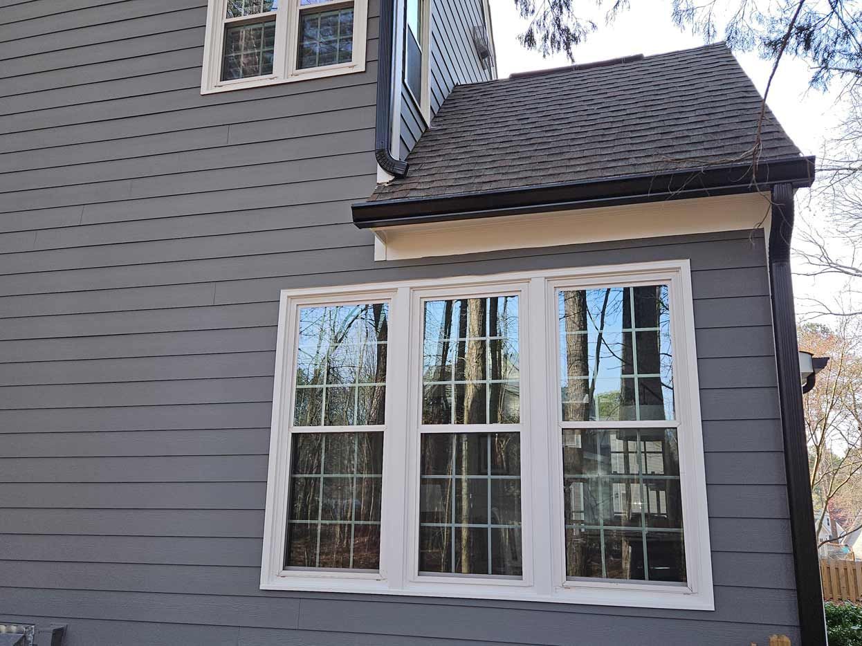 A gray house with white windows and a roof.
