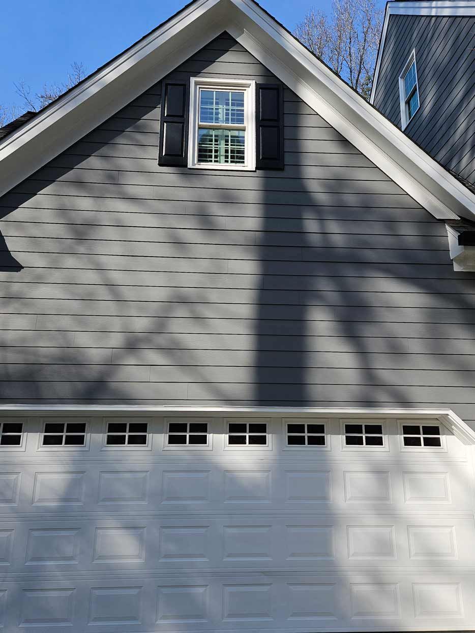 A gray house with a white garage door and a window.