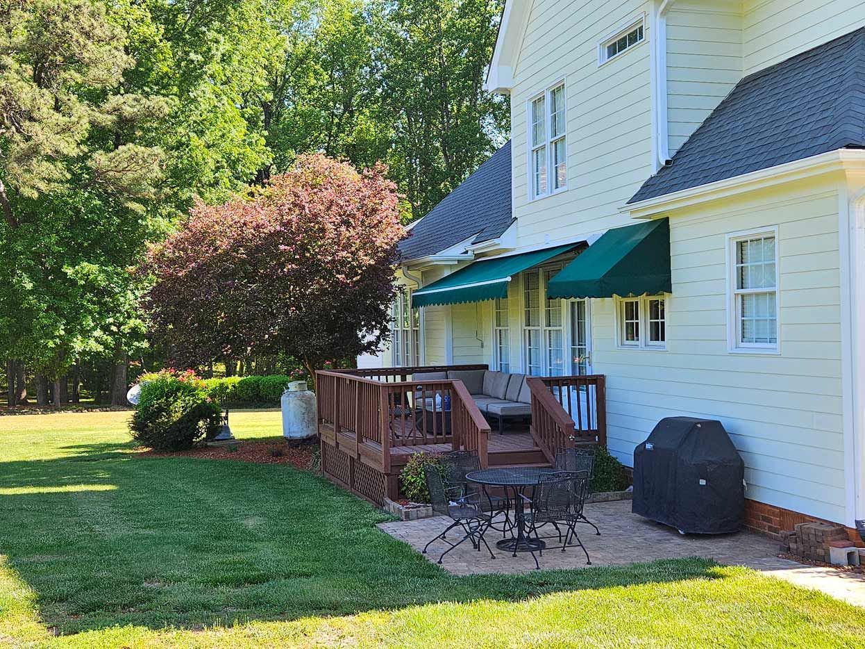 A large white house with a deck and patio area in front of it.