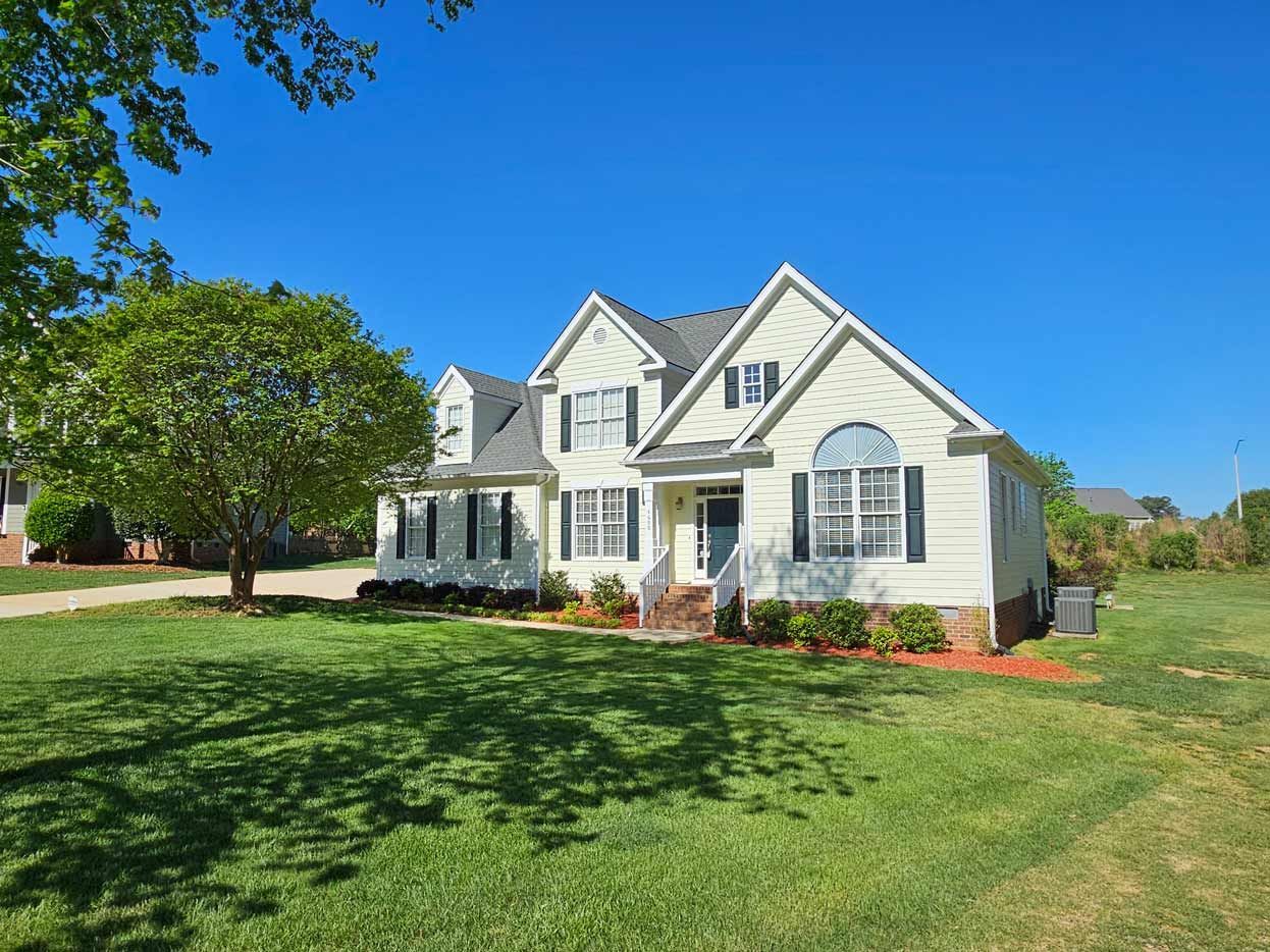 A large white house with a large lawn in front of it.