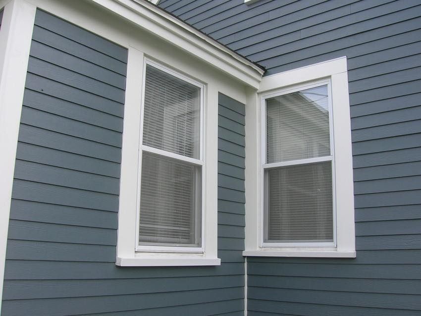 A blue house with white trim and two windows